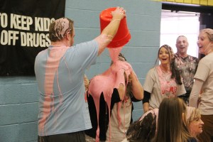 Teacher Tim Gombar pours pink slime on top of fellow teacher Michele Bittner.