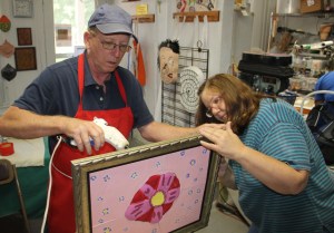 Instructor Craig Bulger and artist Irene Miller work together to frame a 5-piece ceramic art piece.