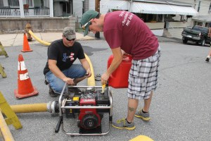 East End Fire Company firefighters Evan "Moose" Bortner (left) and Tom "Tweak" Nelson check the fuel on a water pump used at the intersection of Market and East Union Street. Firefighters remained at the site since 6 AM this morning. Not pictured were firefighters Terry Davis, Dustin Dougherty, and Julie Lesniak.