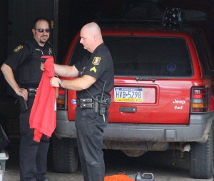 Tamaqua police officers Anthony Stanell, left, and detective Corporal Henry Woods investigate the scene. In the back is a red 1996 Jeep Grand Cherokee Laredo.