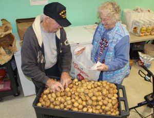 Volunteer John "Jack" Tuite and social worker Esther Stofocik fill bags with baby potatoes for distribution.