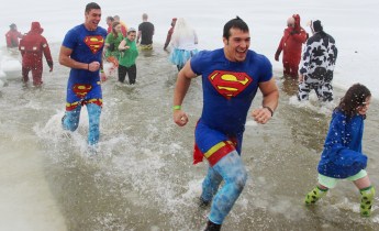 Wearing Superman outfits, Tamaqua YMCA members Zach Evans, left, and Garth Lakitsky run out of the 36 degree water after completely submerging themselves.