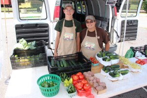 Carson Schoener and Liz Leiby show some of their produce during Saturday's market at the train station parking lot.