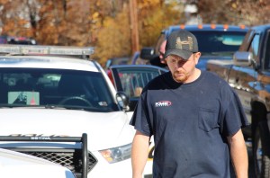 Volunteer firefighter Tim Phillips holds his head down while Tamaqua Police Corporal Henry Woods talks to the suspect in the back of a police car.